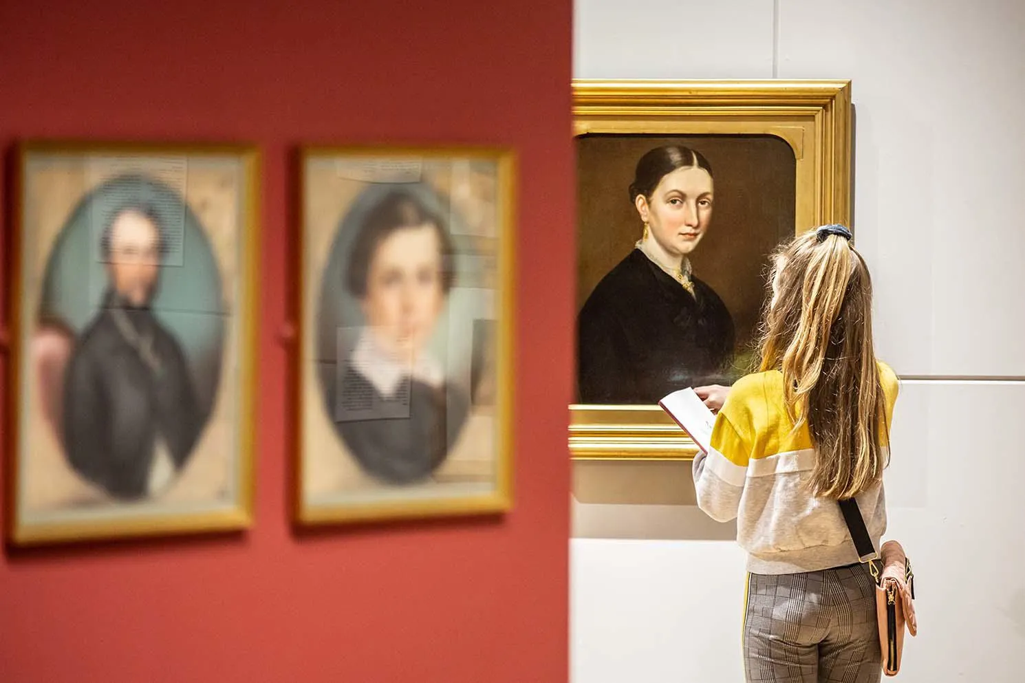 Young woman studying a portrait in the gallery