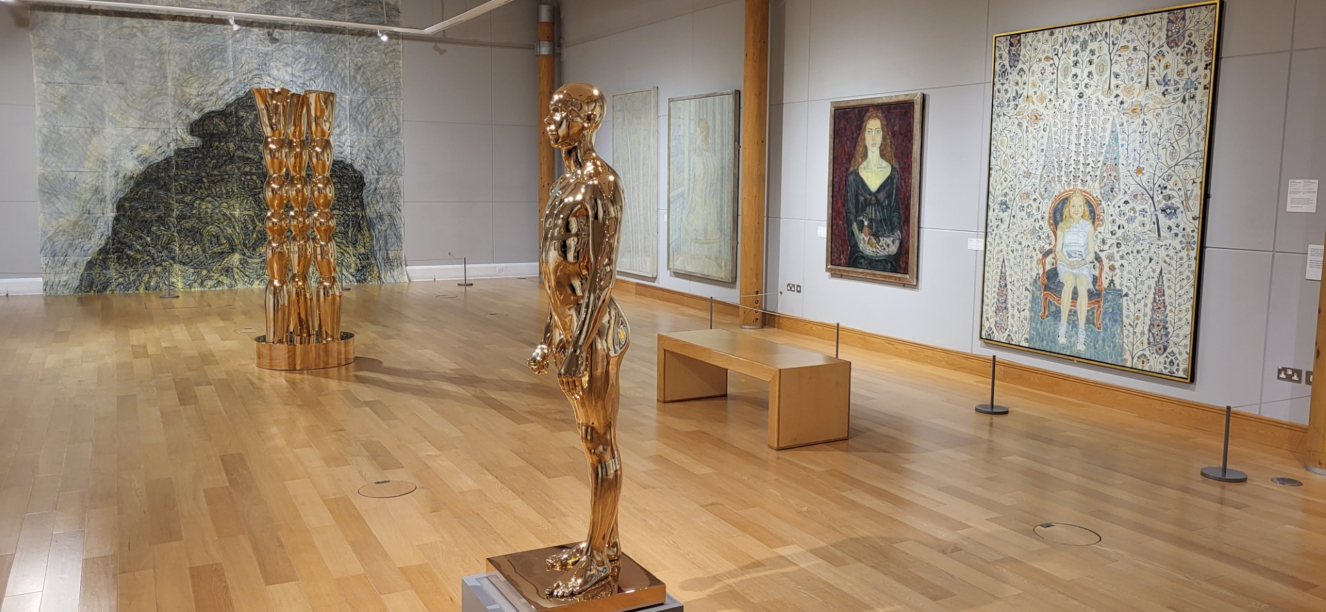 A gallery shot of the young man standing, three trees and drawing on the back wall.